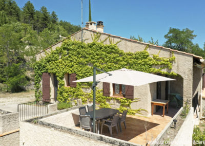 Terrasse avec parasol et salon de jardin devant la maison