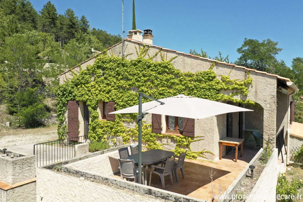 Terrasse avec parasol et salon de jardin devant la maison