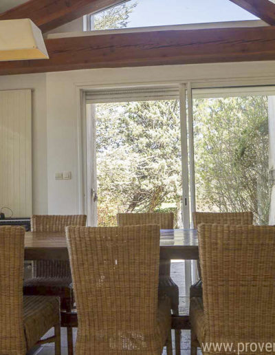 L'espace salle à manger avec sa grande table en bois pouvant accueillir 8 personnes, baigné de lumière grâce à ses ouvertures sur l'extérieur et la charpente en bois apportant tout le charme à la location de vacances Les Gavottes située au Revest des Brousses, au cœur de la Provence.