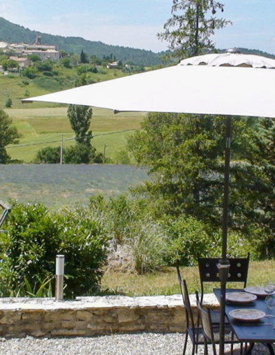 L'allée devant le salon permet d'accueillir une belle table de jardin pour des repas conviviaux en extérieur en profitant de la vue dégagée sur la nature environnante et le village pittoresque formant un panoramique de carte postale pour des vacances agréables au sein de la location saisonnière Les Gavottes, située au Revst des Brousses, au cœur de la Provence.