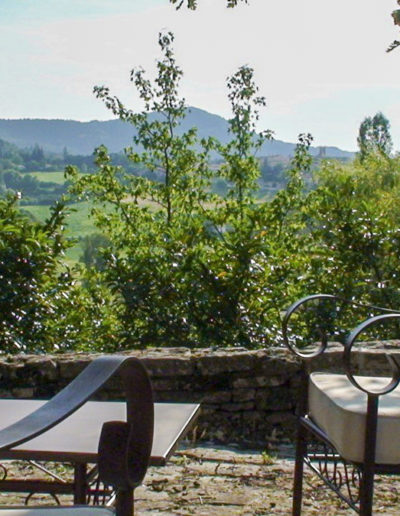 Un salon de jardin à l'ombre d'un arbre protecteur avec une vue dégagée sur la nature environnante, au calme absolu, pour un moment de détente et de plenitude dans le jardin de la location de vacances Les Gavottes située au Revest des Brousses au cœur de la Provence.