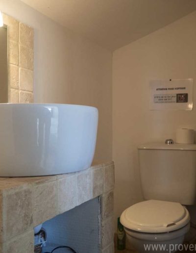 Toilette de l'étage, sous pente avec son plan vasque en travertin, une vasque blanche posée tout en sobriété dans la location de vacances Les Gavottes au Revest des Brousses au cœur de la Provence.
