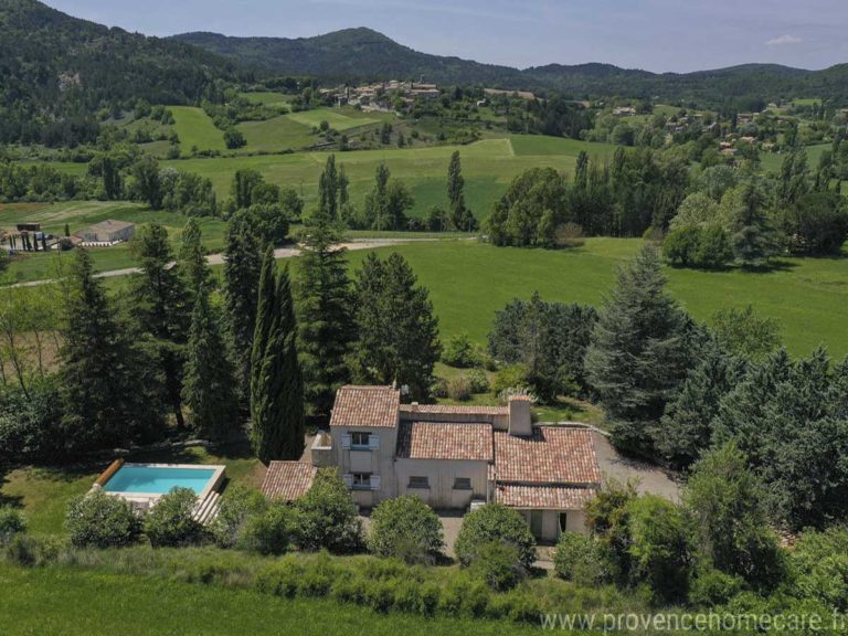 Vue aérienne de la maison et son environnement verdoyant avec la multitude d'arbres entourant la maison pour apporter ombre et fraicheur et en panoramique le village pittoresque et les champs à perte de vue. La maison de vacances Les Gavottes est située sur la commune du Revest des Brousses, au calme absolu, sans vis à vis pour profiter de la nature provençale.