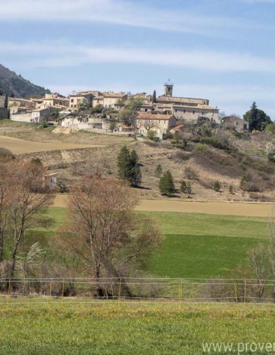 Vue panoramique sur le village avec son clocher et la nature environnante depuis la grande baie vitrée du salon de la location de vacances Les Gavottes située au Revest-des-Brousses au cœur de la Provence.