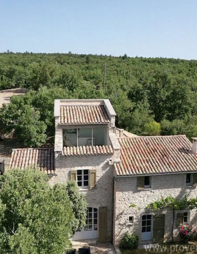 Vue aérienne de la façade principale avec le pigeonnier et son solarium aux larges baies vitrées ouvrant sur la nature environnante de la location de vacances La Poncette à Reillanne en Luberon.