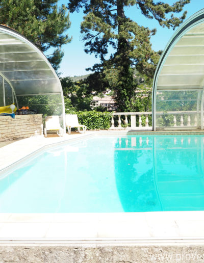 La piscine avec son eau translucide sous son grand dome transparent laissant percevoir l'environnement arboré de la location de vacances Le Castellas située à Manosque en Luberon.