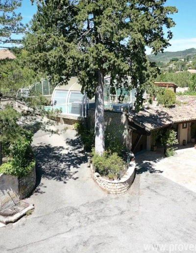 Vue du ciel de la piscine avec sa couverture en forme de dome et la grande terrasse avec la table de ping pong et la cuisine d'été équipé d'un four à bois et d'une grande table pour des repas festifs au sein de la location de vacances Le Castellas située à Manosque au cœur du Luberon.