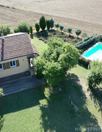 Vue du ciel de la maison avec le jardin arboré et la piscine ensoleillée le tout entouré par les champs avoisinant pour un séjour sous le signe de la tranquillité dans la location de vacances Les Lavandins située à Lurs en Provence.