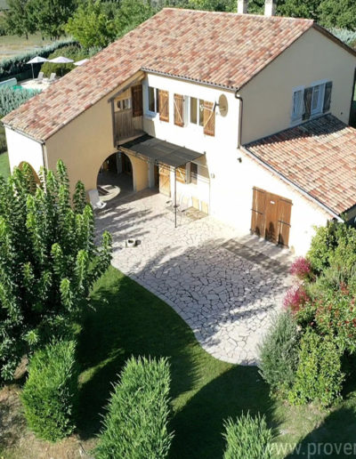 La maison dans son ensemble, vue du ciel avec la grande terrasse exposée Est entouré du jardin arboré et verdoyant qui compose la location de vacances Les Lavandins à Lurs, en Provence.