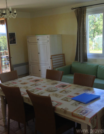 La pièce de vie du T4 avec sa baie vitrée ouvrant sur le balcon en bois et sa grande fenêtre donnant sur la jardin apportant une belle source de lumière équipée d'une table pouvant recevoir 6 à 8 personnes, un large canapé confortable et un décor sobre pour des vacances agréables dans la location Les Lavandins située à Lurs, au cœur de la Provence.