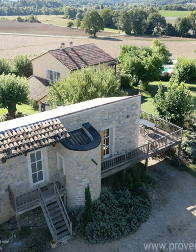 Au premier plan la façade avant de La Santoline avec l'escalier donnant accès à l'entrée de la maison, la terrasse exposée au soleil le jardin arboré et la maison Les Lavandins en second plan composant le domaine La Tuilière, locations de vacances à Lurs, au cœur de la Provence, au milieu des champs.