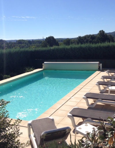 La grande piscine bien exposée, baignée de lumière avec ses transats et ses parasols pour des moments de détente dans la location de vacances Les Lavandins à Lurs en Provence.
