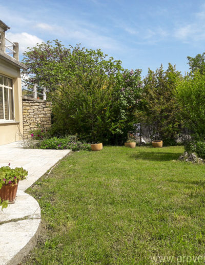 La façade du rez-de-jardin avec ses grandes baies vitrées, la terrasse et le jardin verdoyant baigné de lumière atout charme de la location de vacances Le Fontauris située à Forcalquier au cœur de la Provence