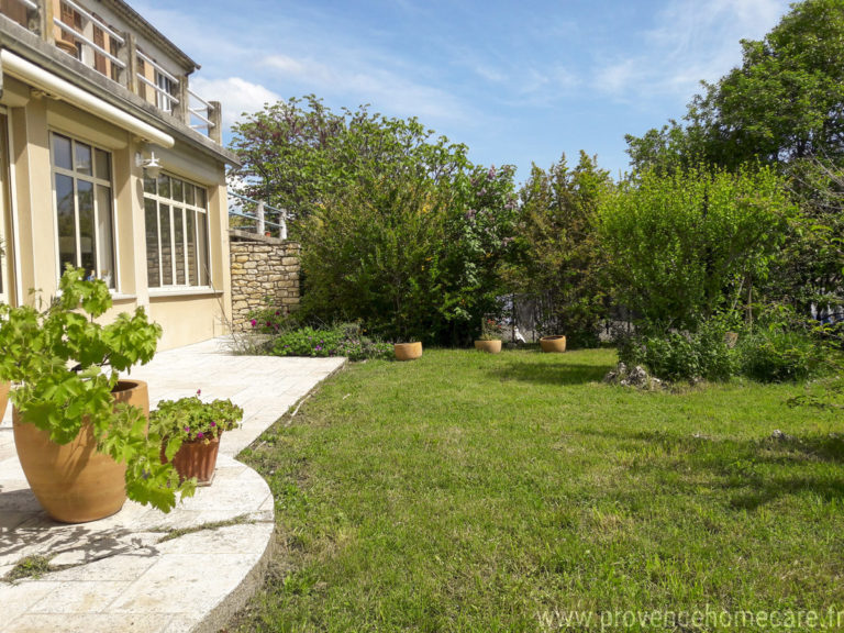 La façade du rez-de-jardin avec ses grandes baies vitrées, la terrasse et le jardin verdoyant baigné de lumière atout charme de la location de vacances Le Fontauris située à Forcalquier au cœur de la Provence