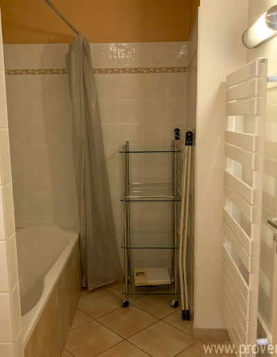 La salle de bain avec baignoire et sèche serviette, confortable avec des tons lumineux dans la location de vacances Le Fontauris, située au centre de Forcalquier, au cœur de la Provence.