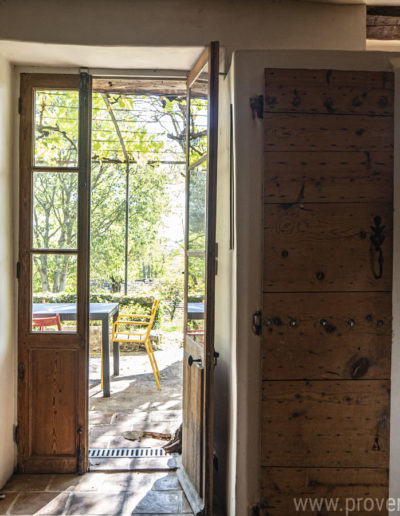 Les ouvertures de la cuisine donnant sur la terrasse et laissant entrevoir la verdure et la nature environnante du jardin de la location de vacances La Norgère à Mane en Provence.