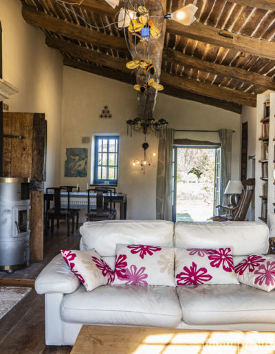 charme et authenticité avec les poutres en plafond, la grande cheminée en pierre, les étagères en bois naturel pour le bel espace salon du gîte de vacances La Norgère à Mane en Provence