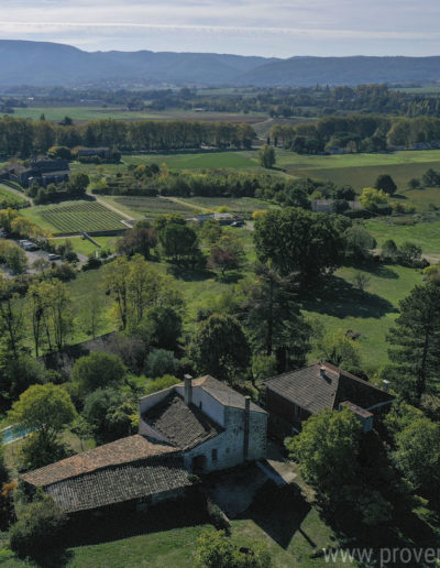 Vue du ciel de la bâtisse en pierre et de son jardin arboré et verdoyant avec piscine pour passer de belles vacances en Provence au gîte de La Norgère à Mane.