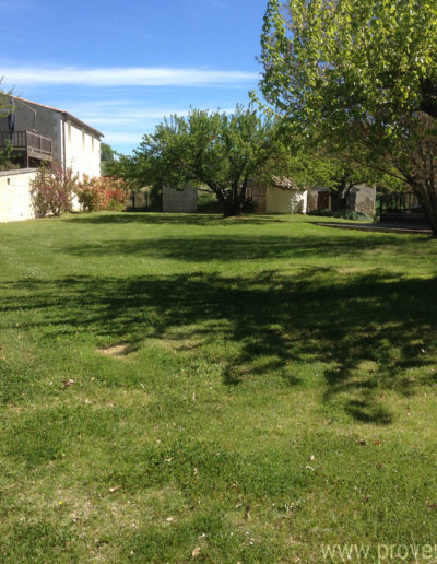 Le jardin verdoyant et arboré baigné de soleil qui entoure la charmante maison de vacances La Santoline située à Lurs au coeur de la Provence.