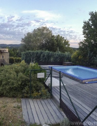 La piscine sans vis à vis dans son environnement de verdure et sa plage en bois, entièrement sécurisé par sa clôture tout autour pour un séjour en toute sérénité dans la location de vacances La Santoline, située à Lurs en Provence.