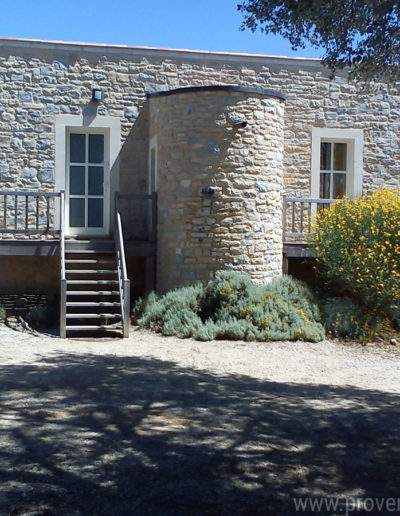 La façade ouest tout en pierre avec l'accès à la maison par un escalier en bois et la végétation environnante pour un dépaysement total dans la location de vacances La Santoline située à Lurs en Provence.