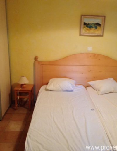 La seconde chambre du T3 au rez-de-chaussée disposant de grand rangement un un décor sobre alliant le bois et les murs jaune soleil dans un esprit provençal pour des vacances agréables au sein de la location de vacances Les Lavandins située à Lurs, au cœur de la Provence.