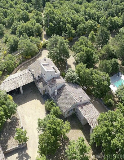 Vue aérienne de l'arrière de la bâtisse, avec l'espace couvert abritant la table de ping-pong, le grand jardin arboré et verdoyant et la piscine pour des moments conviviaux dans la location de vacances La Poncette située à Reillanne en Luberon.