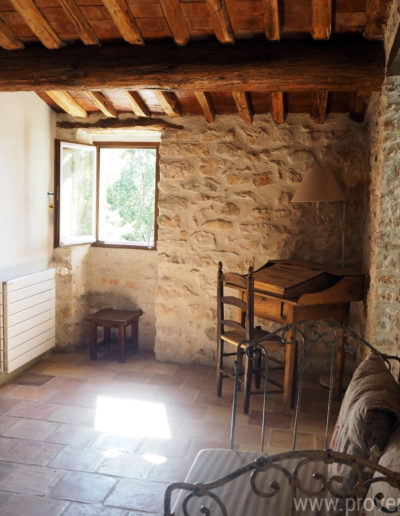 Le charme à l'intérieur de la maison avec son plafond authentique en bois, les pierres apparentes et le mobilier en bois et fer forgé. Confort et authenticité s'allient dans la location de vacances La Poncette située à Reillanne dans le Luberon.