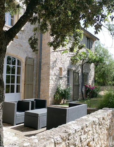La belle façade en pierre, le jardin végétalisé et le salon de jardin confortable qui font tout le charme de la location de vacances La Poncette, située à Reillanne dans le Luberon.