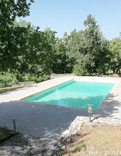 La grande piscine avec son eau claire et limpide, les bains de soleil et l'environnement arboré et ombragé au coeur du jardin de la location de vacances La Poncette à Reillanne en Luberon.