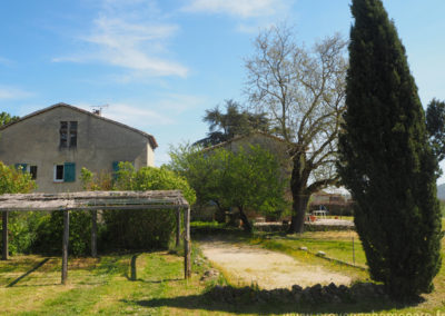 Vue sur le parking et le terrain de boules, arbres, maison gérée par l'agence Provence Home care