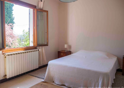 Chambre avec grand lit, chevets et lampes, fenêtre, tapis de sol