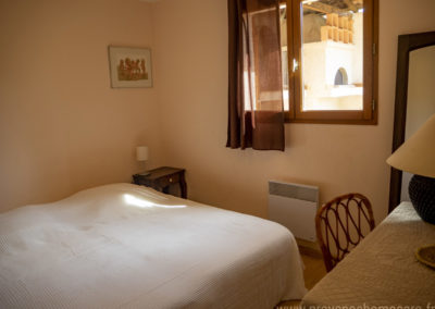 Chambre avec 2 lits simples réunis pour former un lit double, chevets, lampes, cadres décoratifs, fenêtre et rideaux, bureau