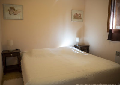 Chambre avec 2 lits simples réunis pour former un lit double, chevets, lampes, cadres décoratifs, fenêtre et rideaux