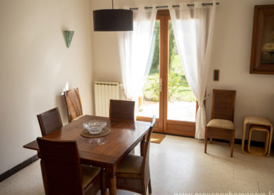 Salle à manger, table avec rallonge, chaises en bois, tableau, porte fenêtre donnant sur terrasse