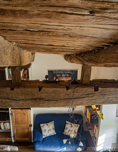 Vue en contreplongée sur le plafond du salon avec ses larges poutres en bois, charme et authenticité son au rendez-vous dans la location de vacances La Norgère à Mane en Provence