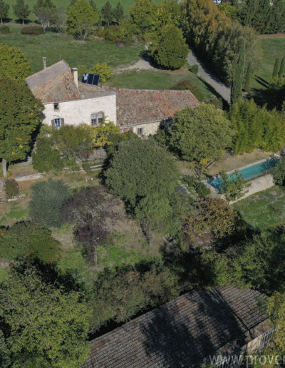 Vue du ciel de la façade avant du gîte de vacances La Norgère avec le jardin arboré, verdoyant, la piscine et la maison des propriétaires à sa gauche. La nature verdoyante de la Provence.