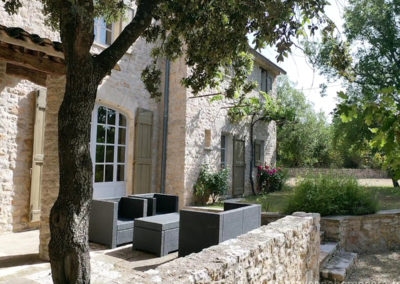 Salon de jardin sur la terrasse en pierres à l'ombre d'un chêne, jardin fleuri, villa gérée par l'agence Provence Home care