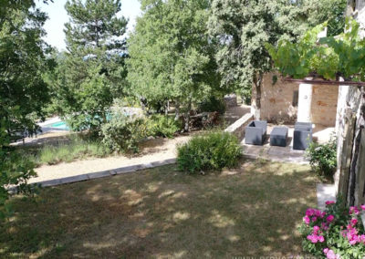 Vue sur jardinet et terrasse avec salon de jardin, nombreux arbres devant la piscine sécurisée, maison gérée par l'agence Provence Home care